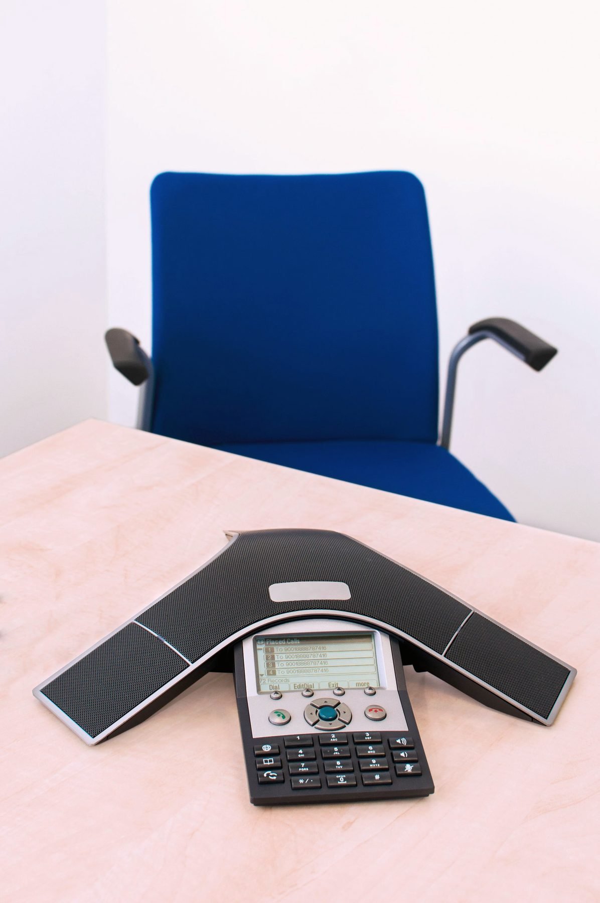 A conference telephone on a desk beside an office chair