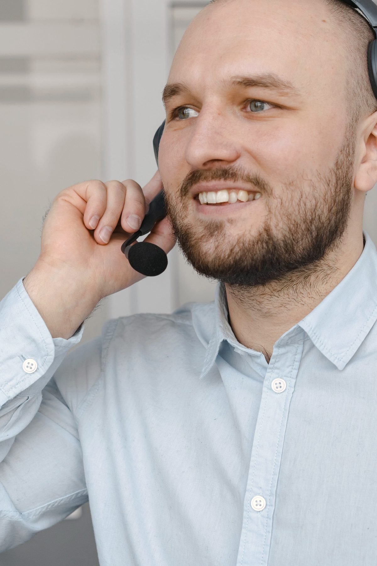 A man smiling while speaking into a headset microphone