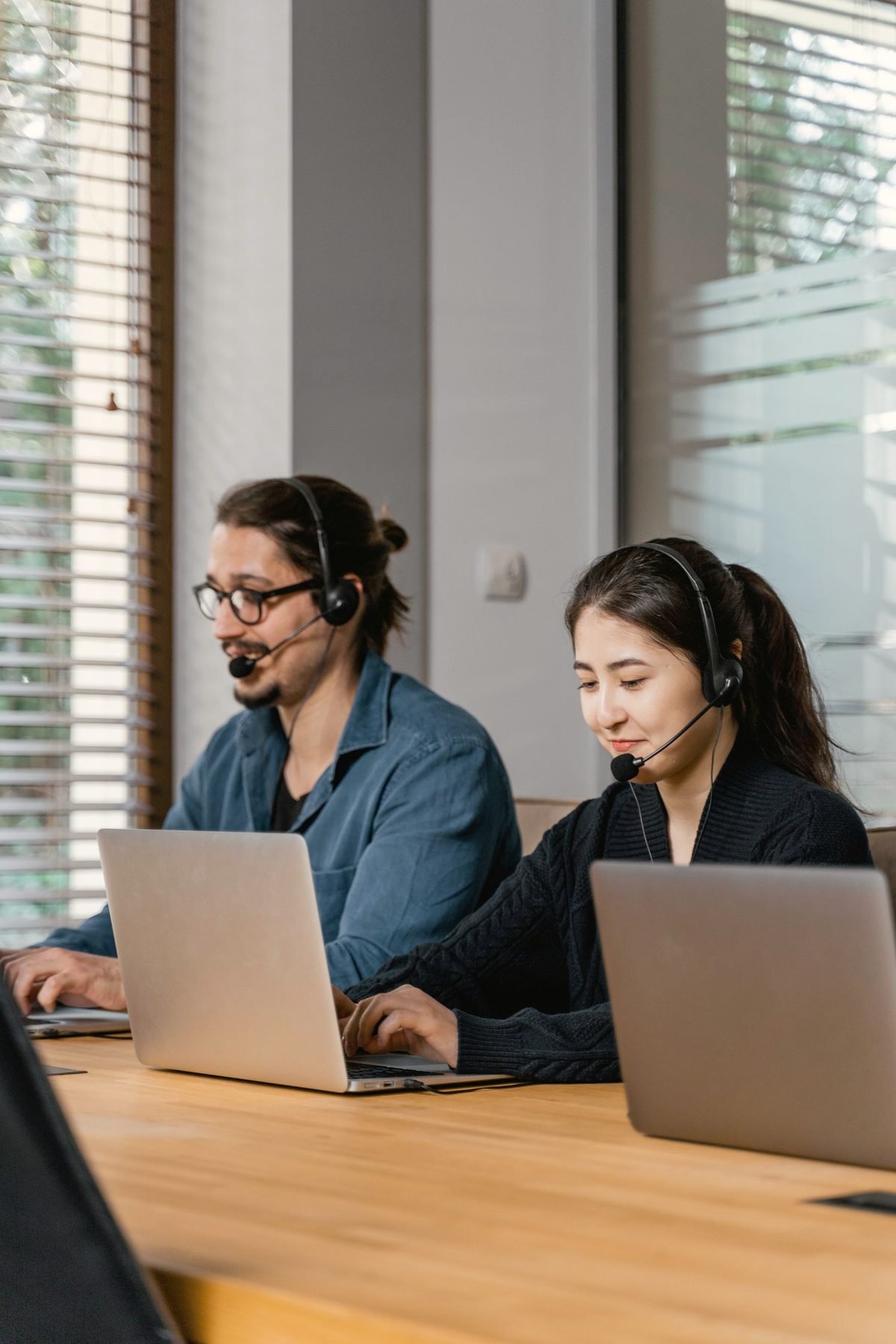 Two operators working side by side at a long desk, both wearing headsets