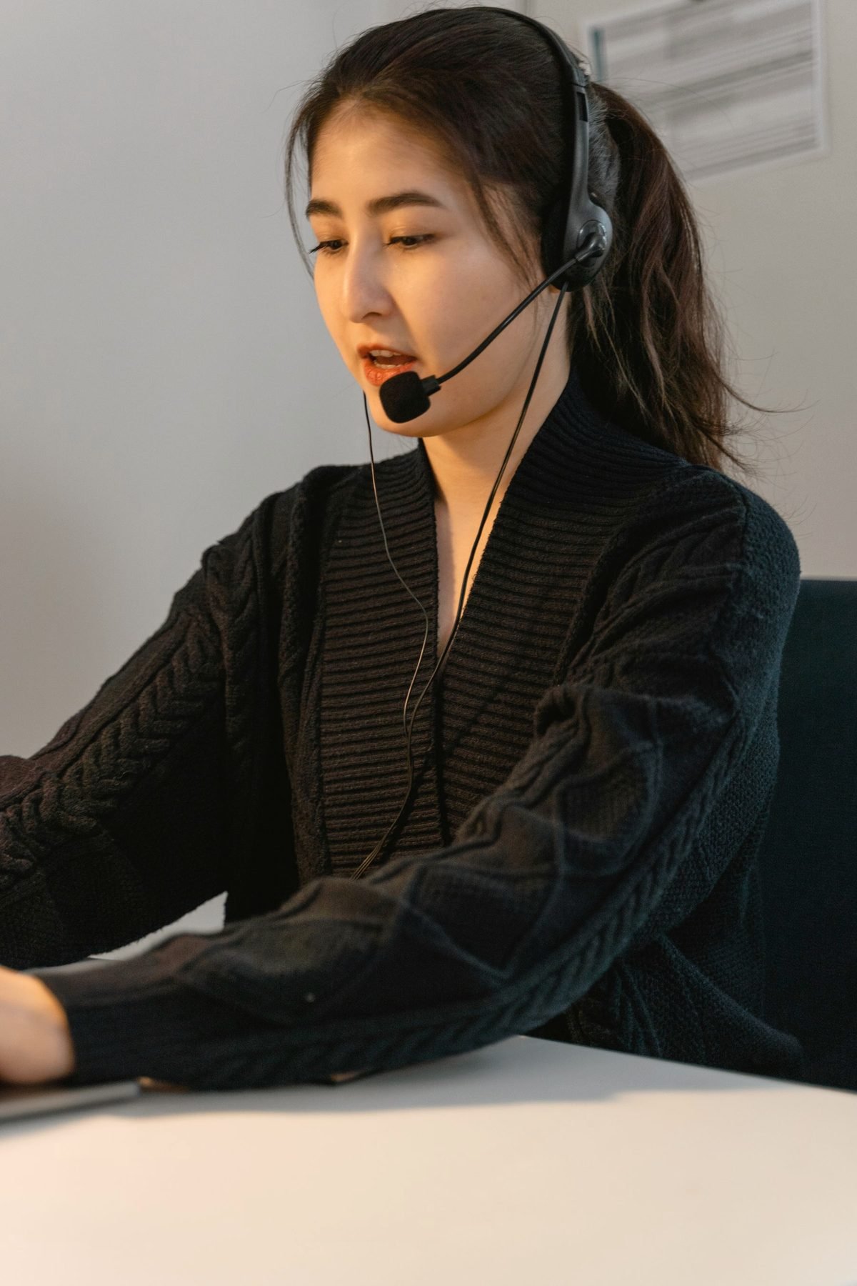An operator wearing a headset listening to a caller at her desk